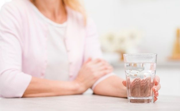 Seorang wanita sedang minum air putiih.