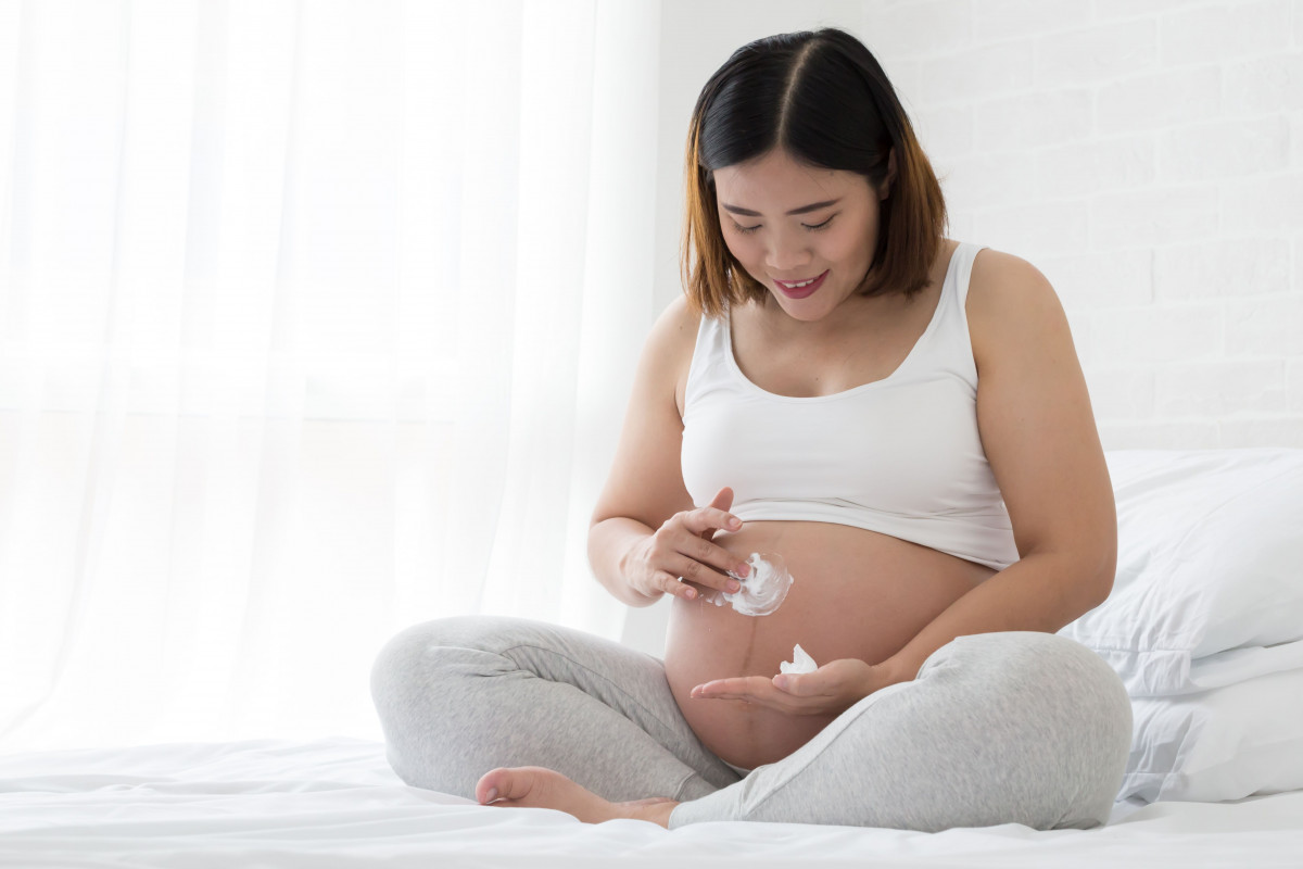 Wanita hamil menggunakan losion. 