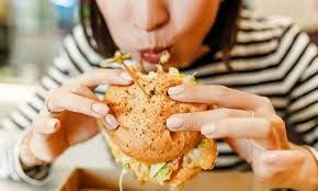 Seorang wanita sedang makan burger.