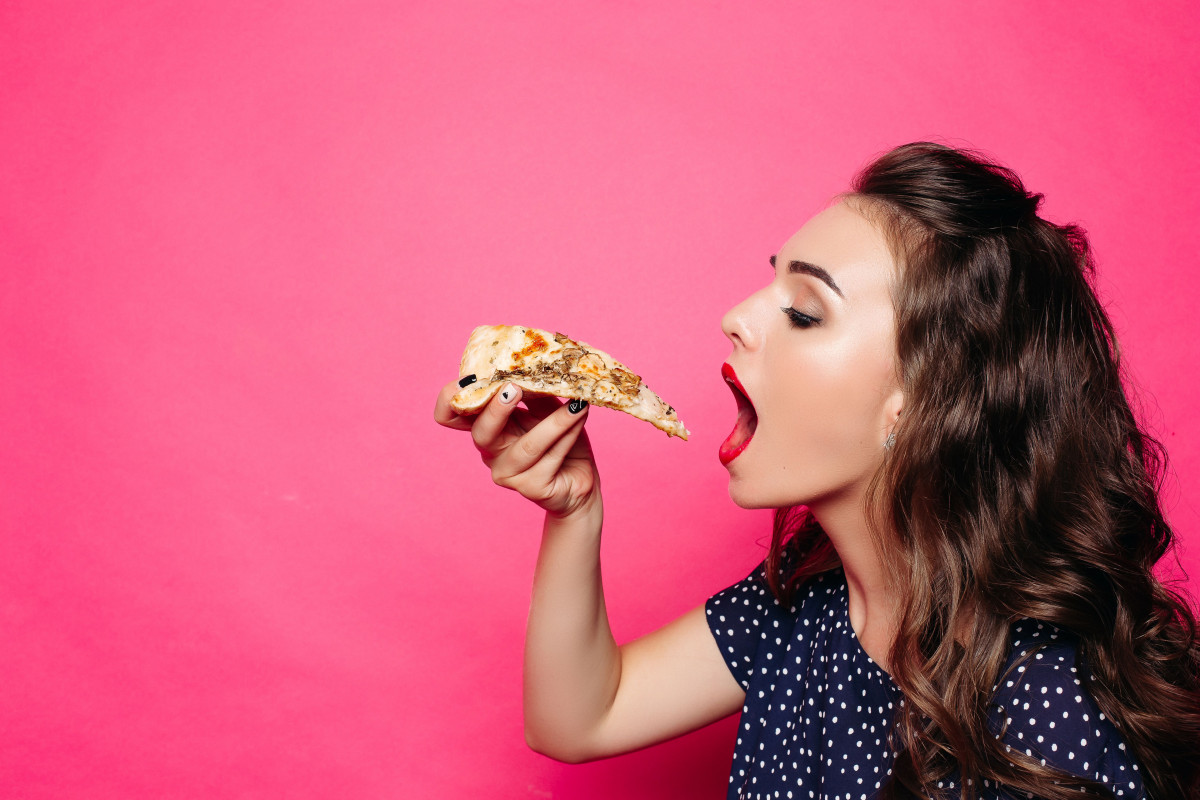 Seorang wanita sedang makan pizza.