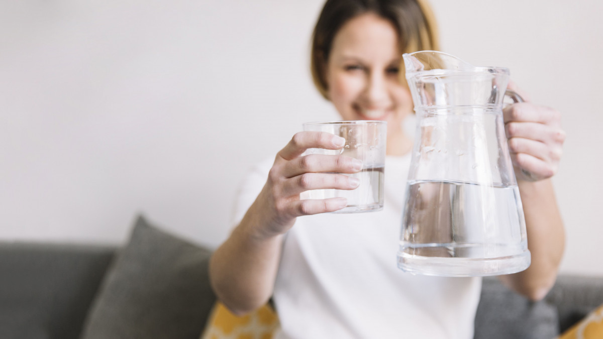 Seorang wanita sedang minum air putih.