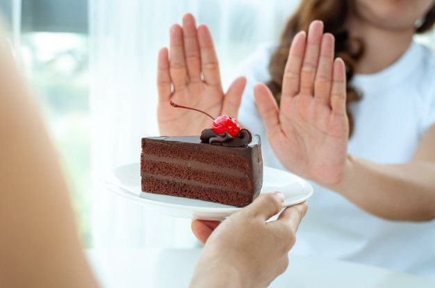 Seorang perempuan mengatakan tidak kepada makanan manis.