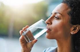 Seorang wanita sedang minum air putiih.