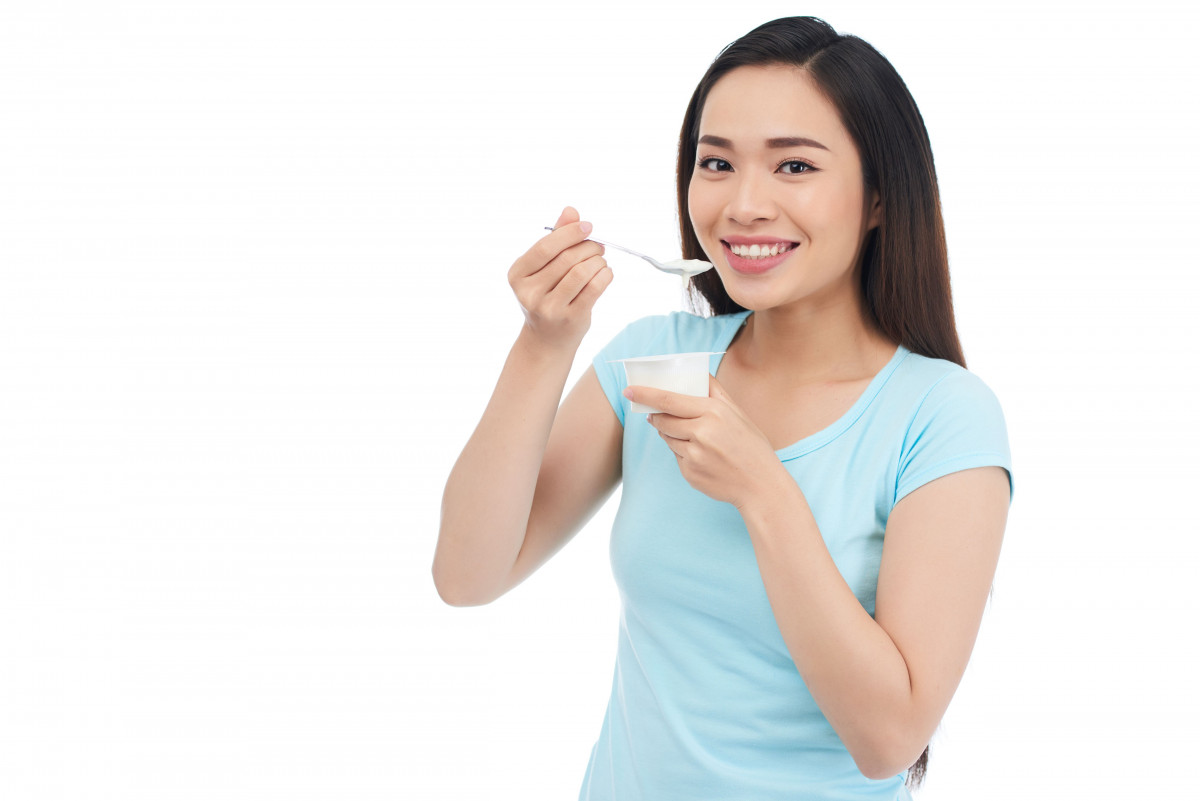 Seorang wanita sedang konsumsi yogurt.