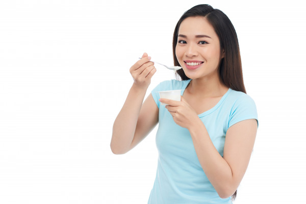 Seorang wanita sedang konsumsi yogurt.