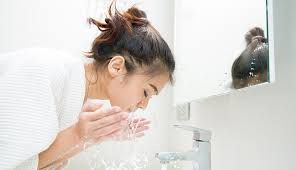 Seorang wanita sedang mencuci wajah.