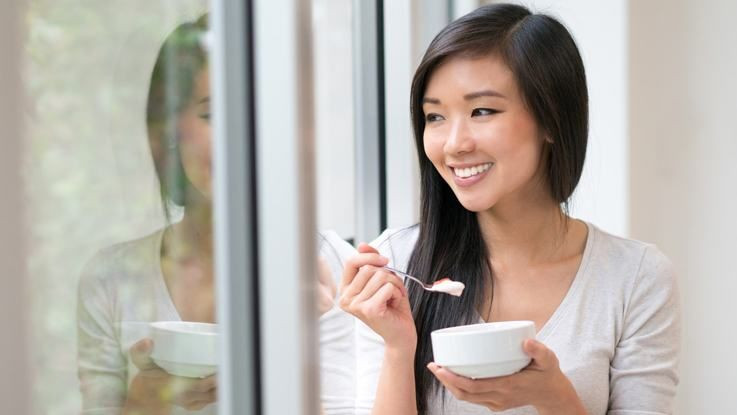 Seorang wanita sedang makan yoghurt.