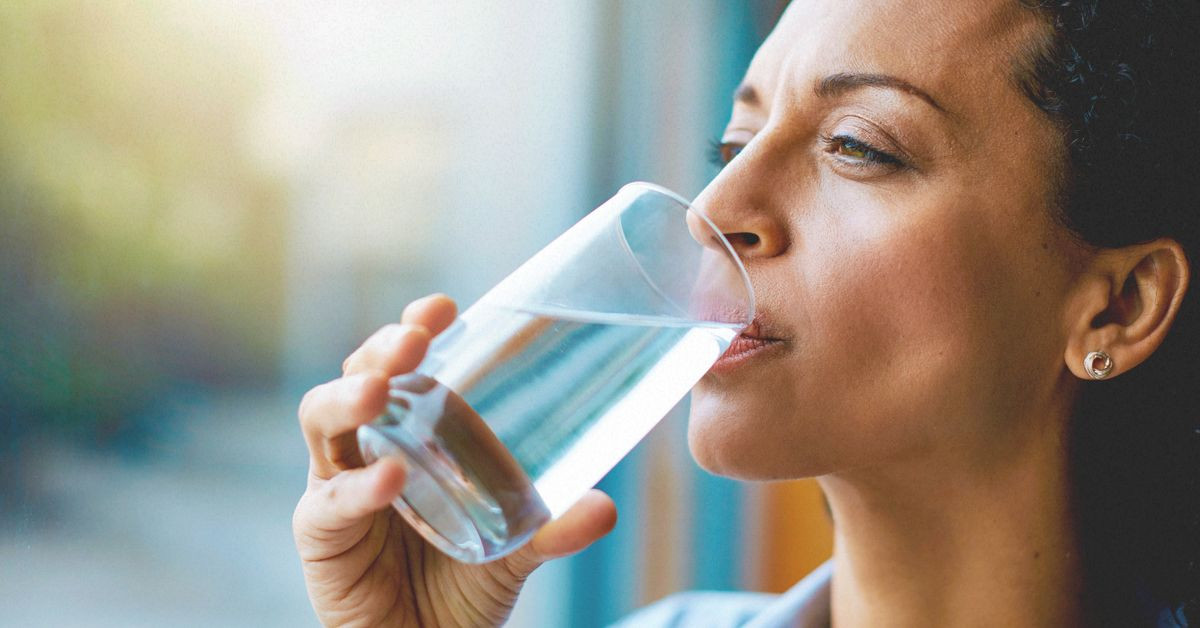 Seorang wanita sedang minum air putiih.