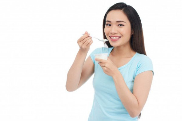Seorang wanita mengonsumsi yogurt sebagai probiotik
