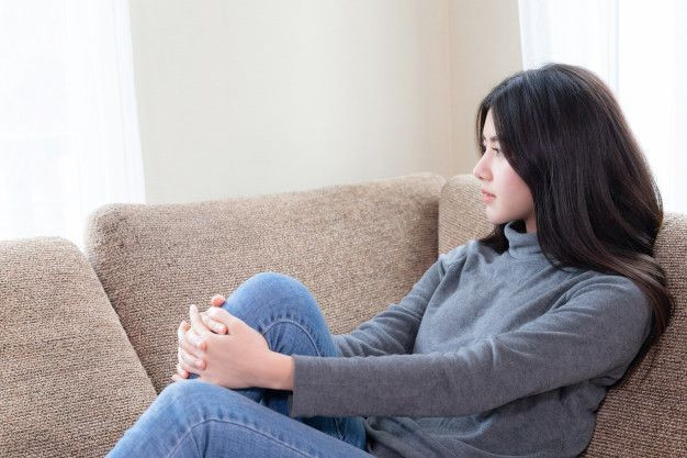 Seorang wanita sedang duduk di sofa.