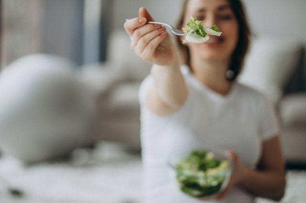 Seorang wanita hamil sedang makan salad.