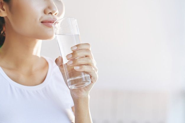 Seorang wanita sedang minum air putiih.