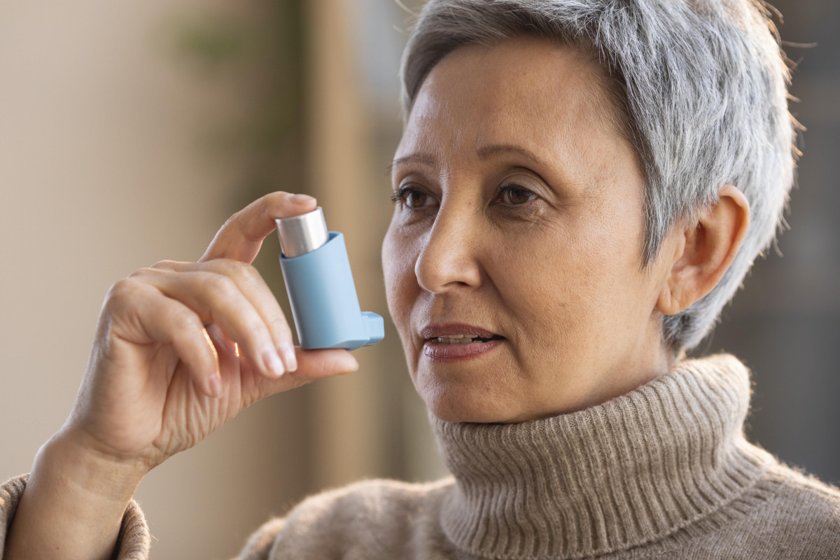 Seorang wanita sedang menggunakan inhaler untuk asma.