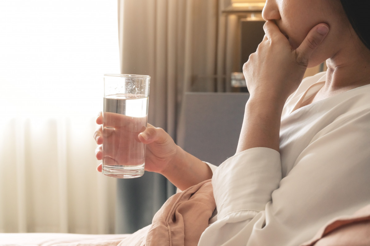 Seorang wanita sedang minum obat.