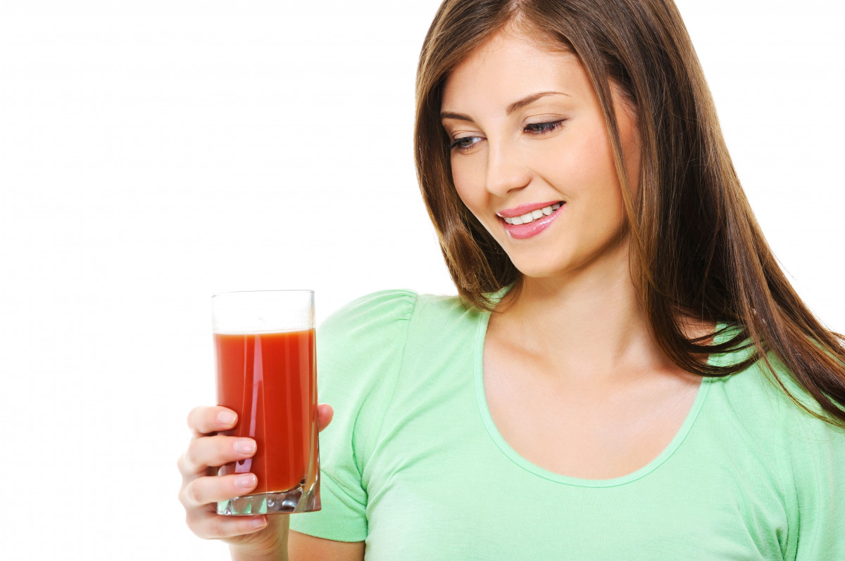 Seorang wanita sedang minum jus tomat