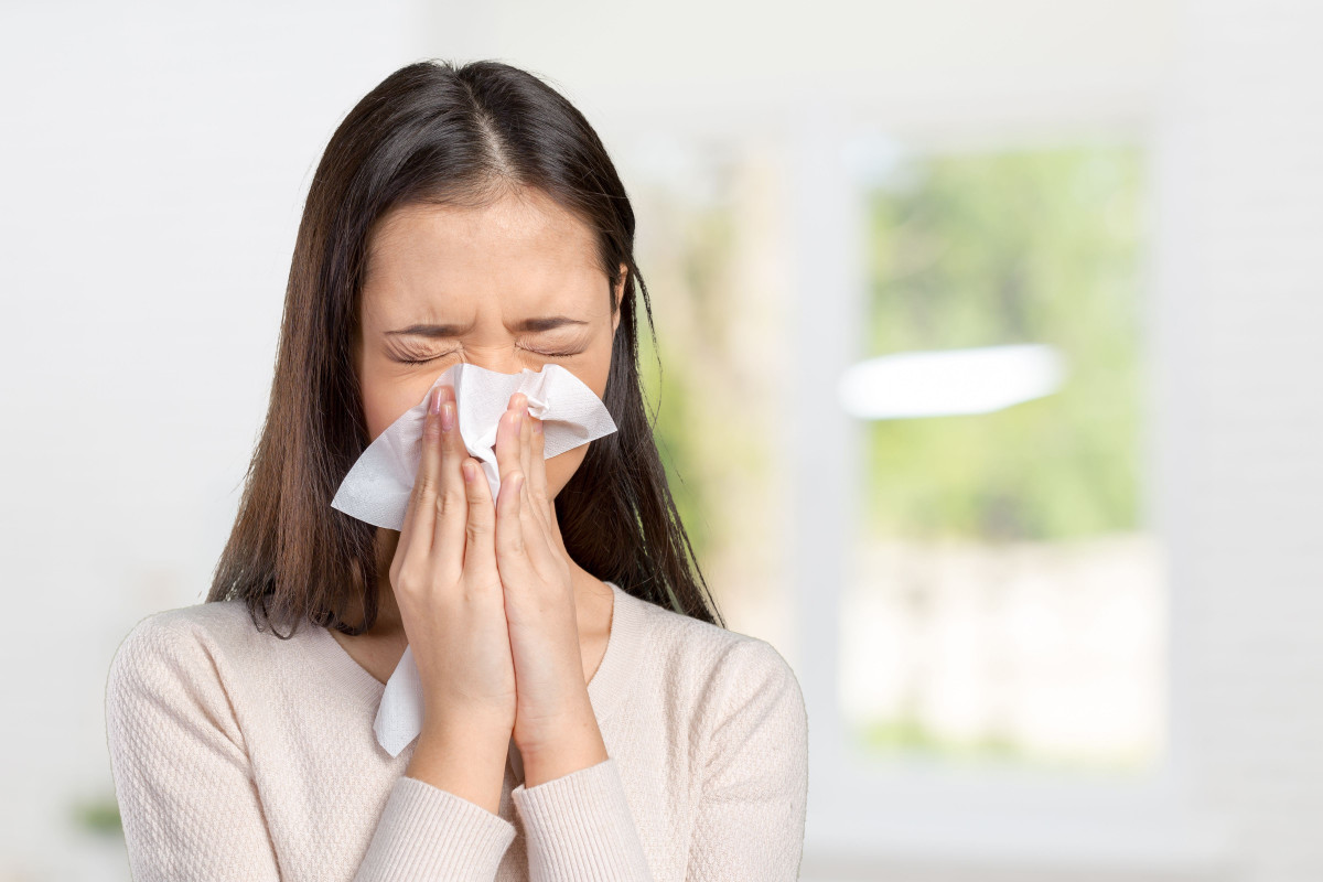 Seorang wanita sedang mengalami flu.